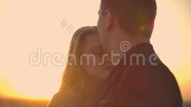 两个情人在日出日落时在俯瞰城市的摩天大楼上拥抱跳舞。 浪漫的场景。